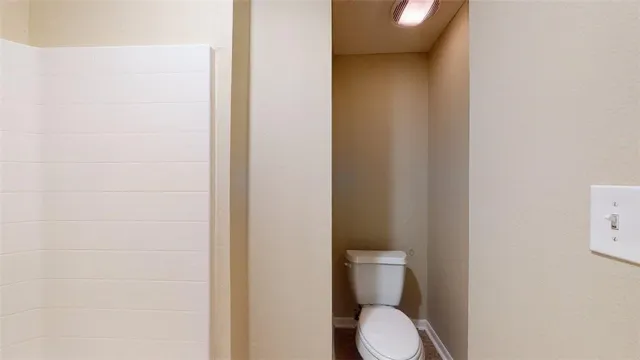 a white toilet sitting next to a white wall