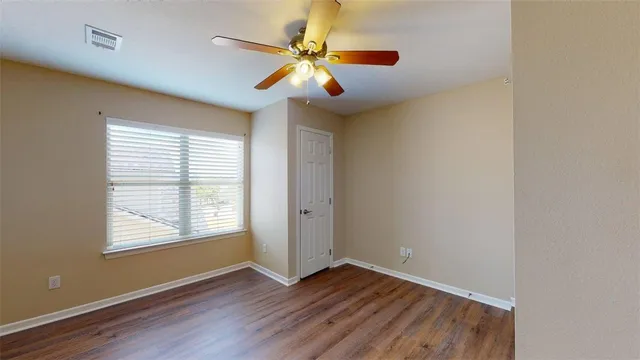 a view of an empty room with window and wooden floor