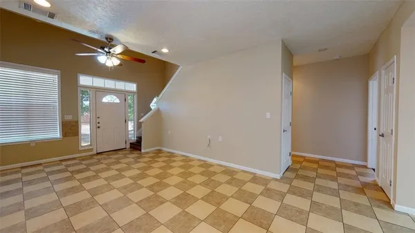 a view of an empty room and window and chandelier fan