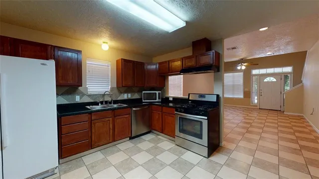 a kitchen with stainless steel appliances granite countertop a stove a sink and a refrigerator