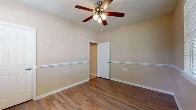 an empty room with wooden floor closet and windows