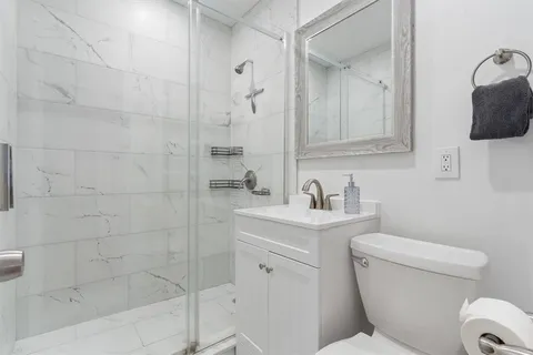 a bathroom with a toilet sink vanity shower and mirror