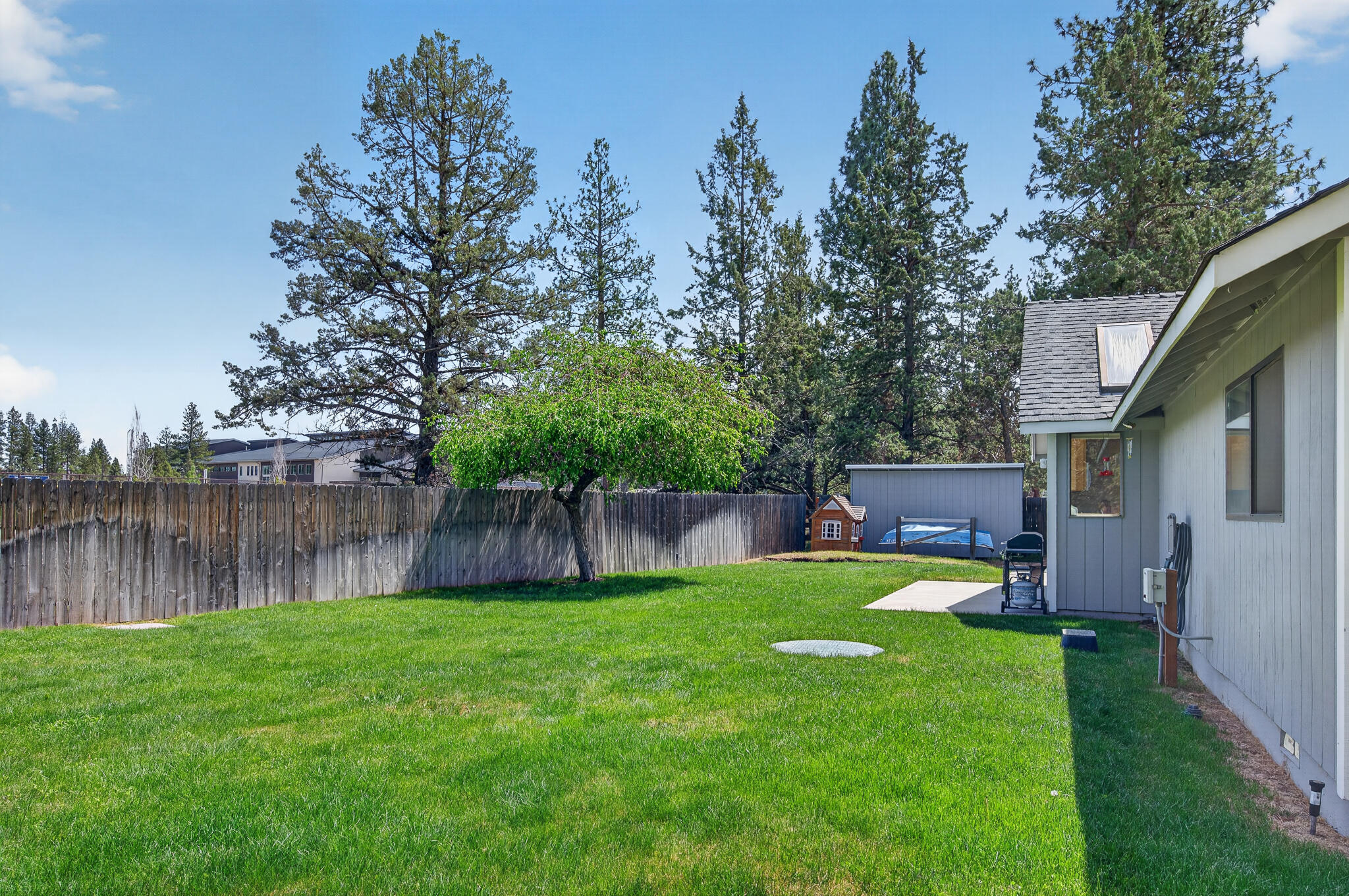 60866 Brosterhous Road Bend, OR 97702 - Photo 5 of 41 a view of a backyard with table and chairs and wooden fence