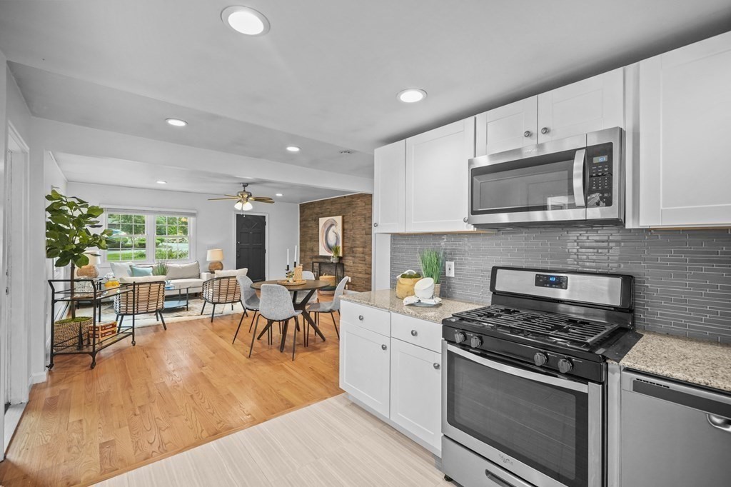 1122 Wood Street Fall River, MA 02721 - Photo 15 of 39 a open kitchen with stainless steel appliances granite countertop a stove top oven a sink dishwasher a dining table and chairs with wooden floor