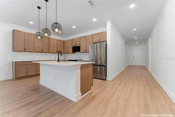 a kitchen with stainless steel appliances granite countertop a sink a stove a refrigerator and island with wooden floor
