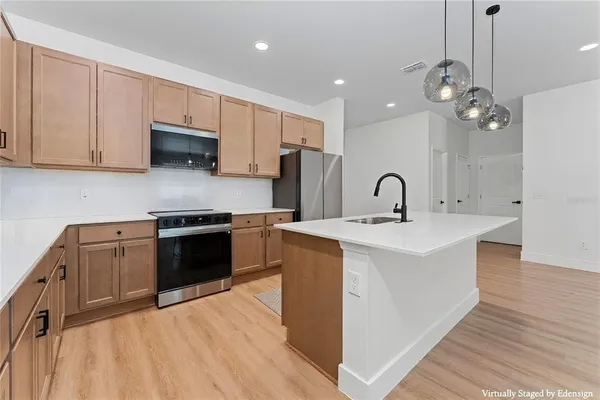 a view of kitchen with kitchen island wooden floor center island and stainless steel appliances