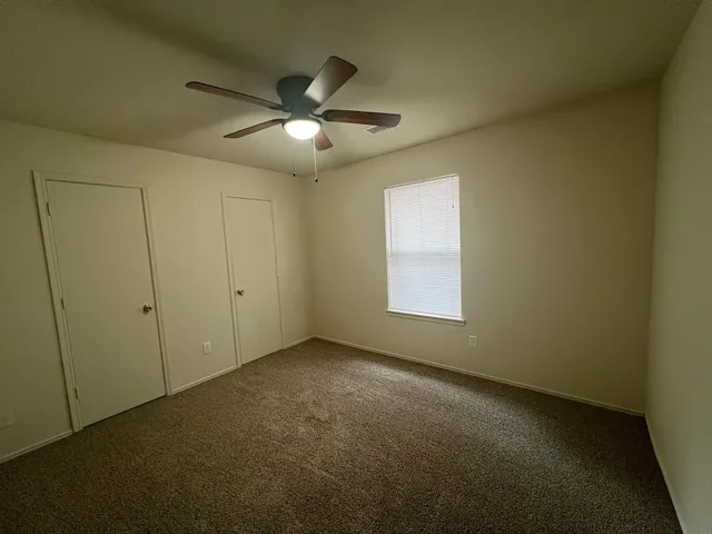 an empty room with a window and a fan