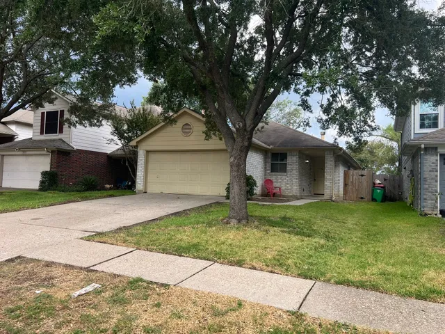a view of a house with a small yard and large tree