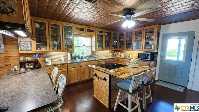 a kitchen with a stove a sink dishwasher a dining table and chairs with wooden floor