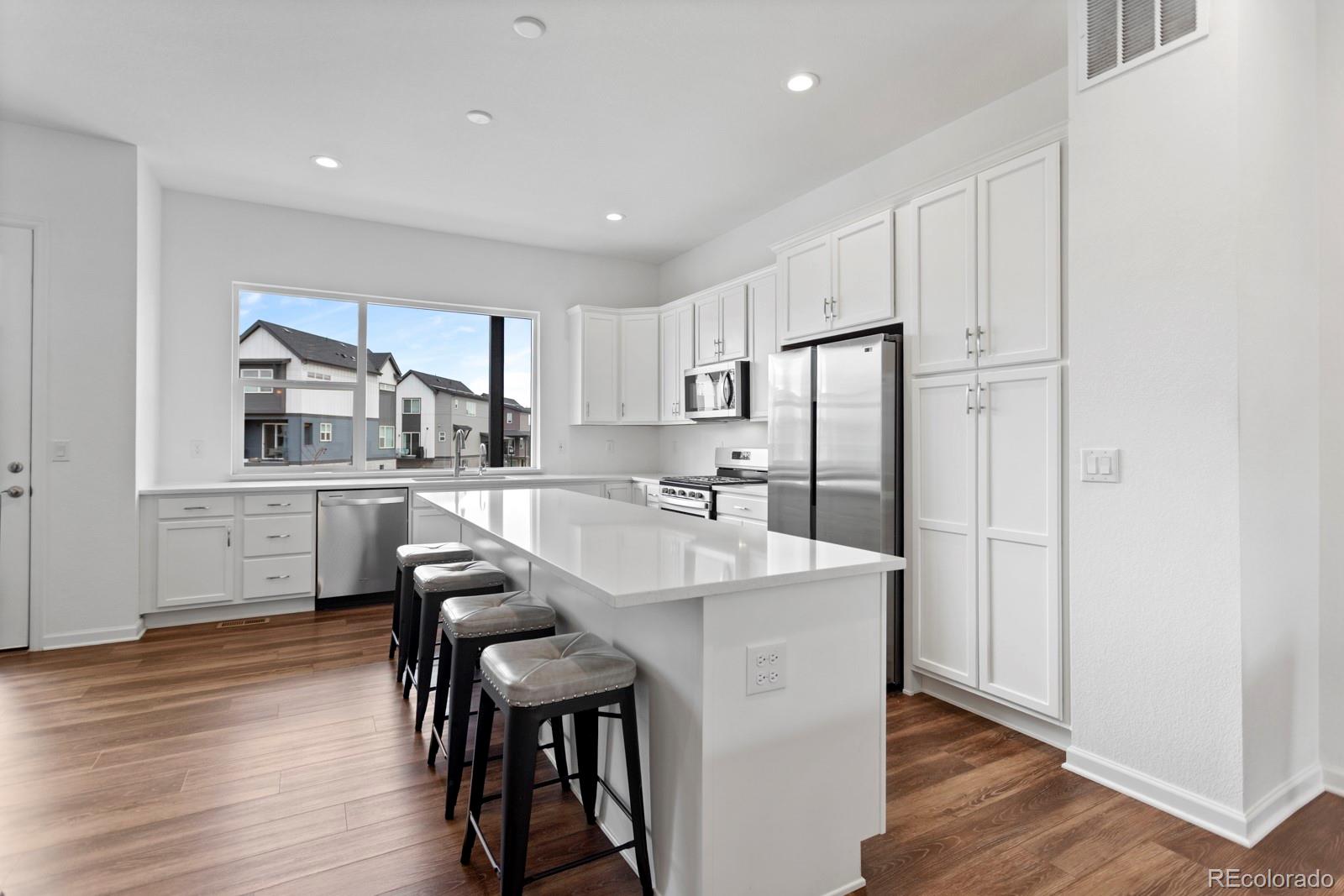 5105 Vivian Street Wheat Ridge, CO 80033 - Photo 5 of 39 a kitchen with stainless steel appliances a dining table chairs refrigerator and cabinets