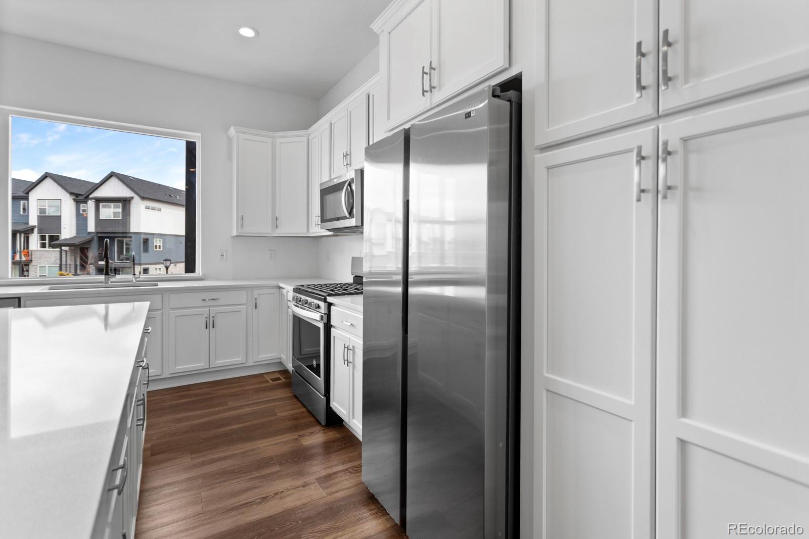 5105 Vivian Street Wheat Ridge, CO 80033 - Photo 9 of 39 a kitchen with a refrigerator a sink and dishwasher with wooden floor