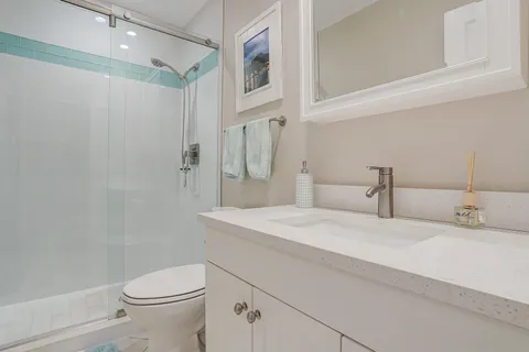 a bathroom with a granite countertop sink a toilet and a shower