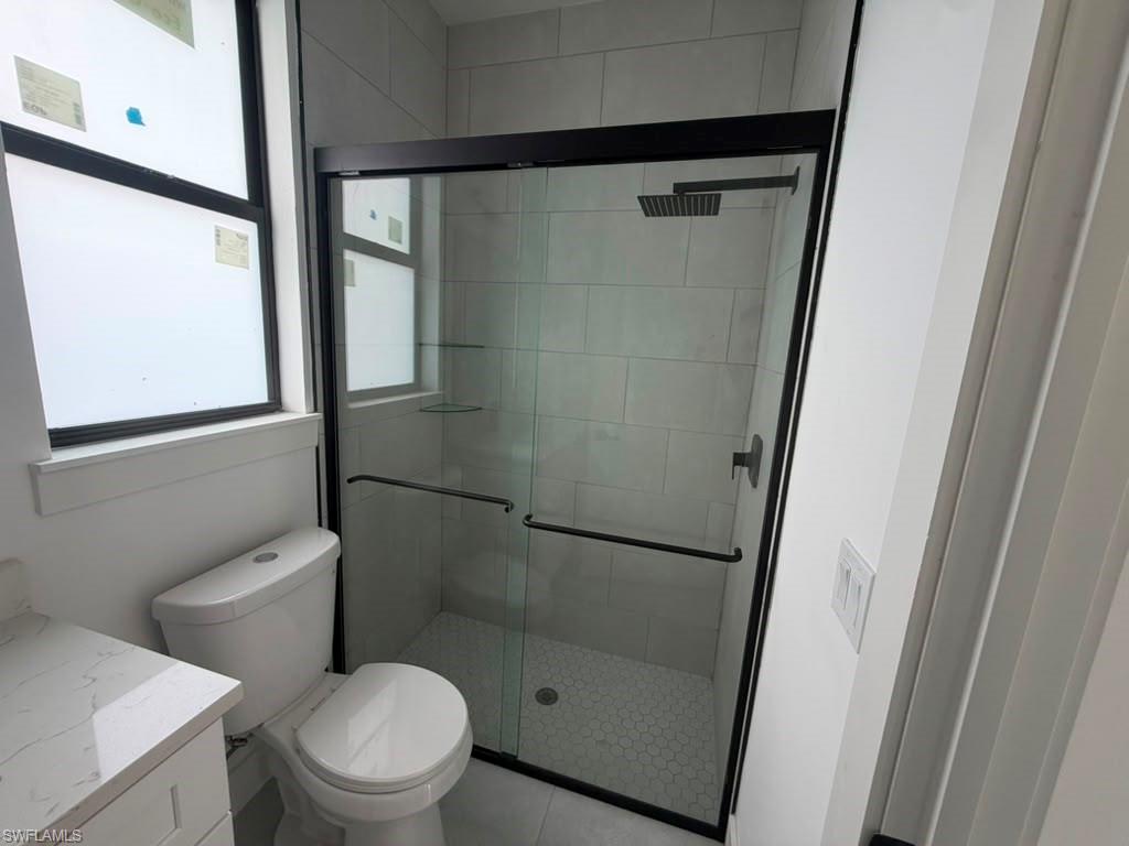 907 Homestead Road South Lehigh Acres, FL 33974 - Photo 39 of 43 Modern bathroom featuring a glass-enclosed shower with matte black hardware, rectangular rain shower head, and hexagonal tile flooring