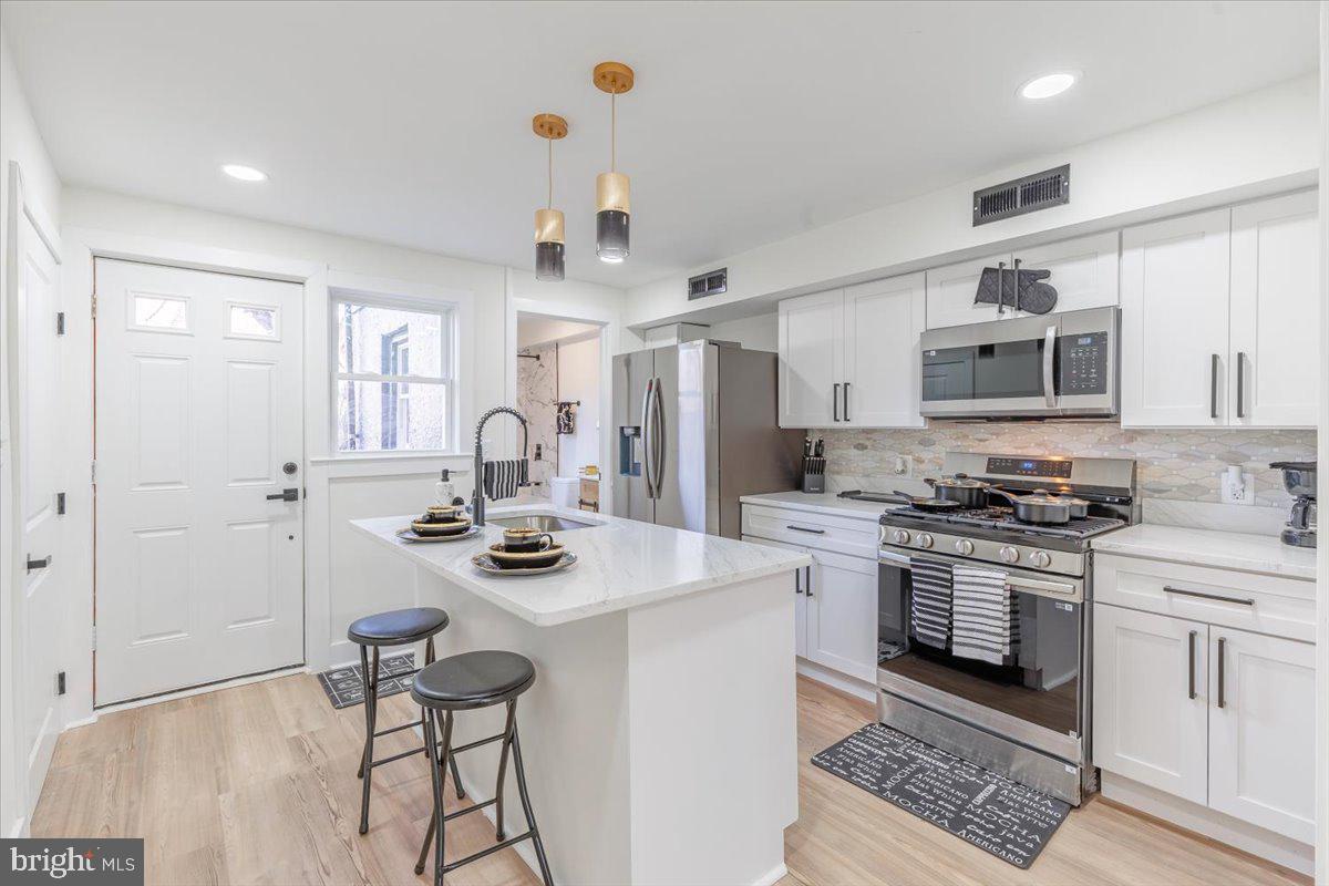 4702 Meade Street Northeast Washington, DC 20019 - Photo 15 of 28 a kitchen with stainless steel appliances granite countertop a stove and white cabinets