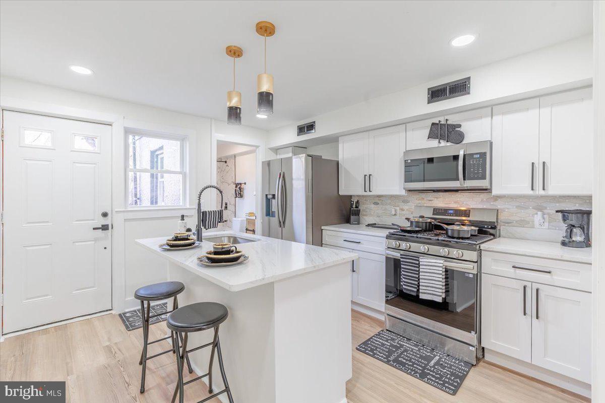 4702 Meade Street Northeast Washington, DC 20019 - Photo 16 of 28 a kitchen with stainless steel appliances kitchen island granite countertop a stove and white cabinets