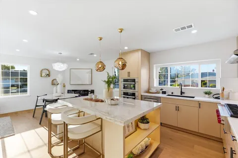 a kitchen with a stove a sink a dining table and chairs