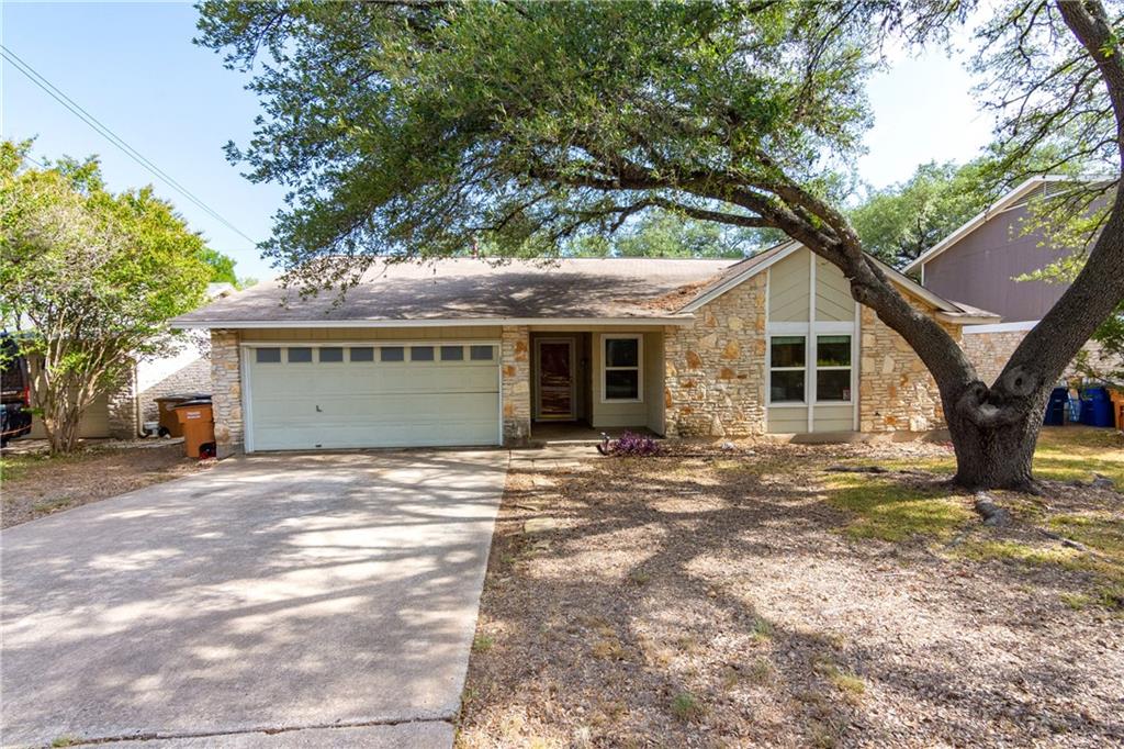 View of front of property with stone siding, driveway, and a garage