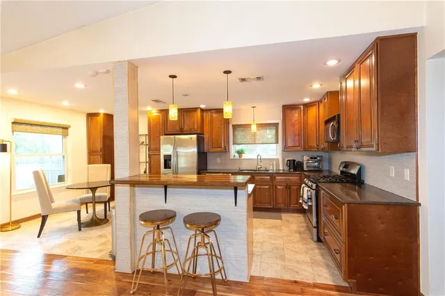 a kitchen with stainless steel appliances a stove a sink a oven a dining table and chairs