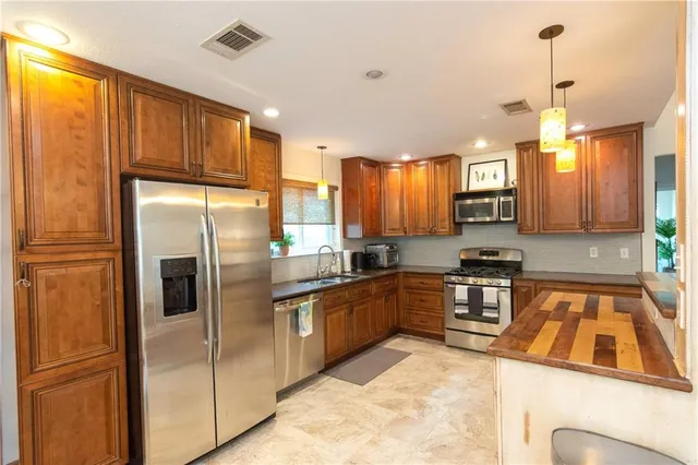 a kitchen with stainless steel appliances granite countertop a refrigerator a sink dishwasher a stove and a refrigerator with wooden floor