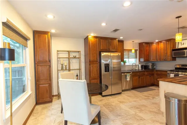 a kitchen with stainless steel appliances granite countertop a refrigerator a stove and a sink