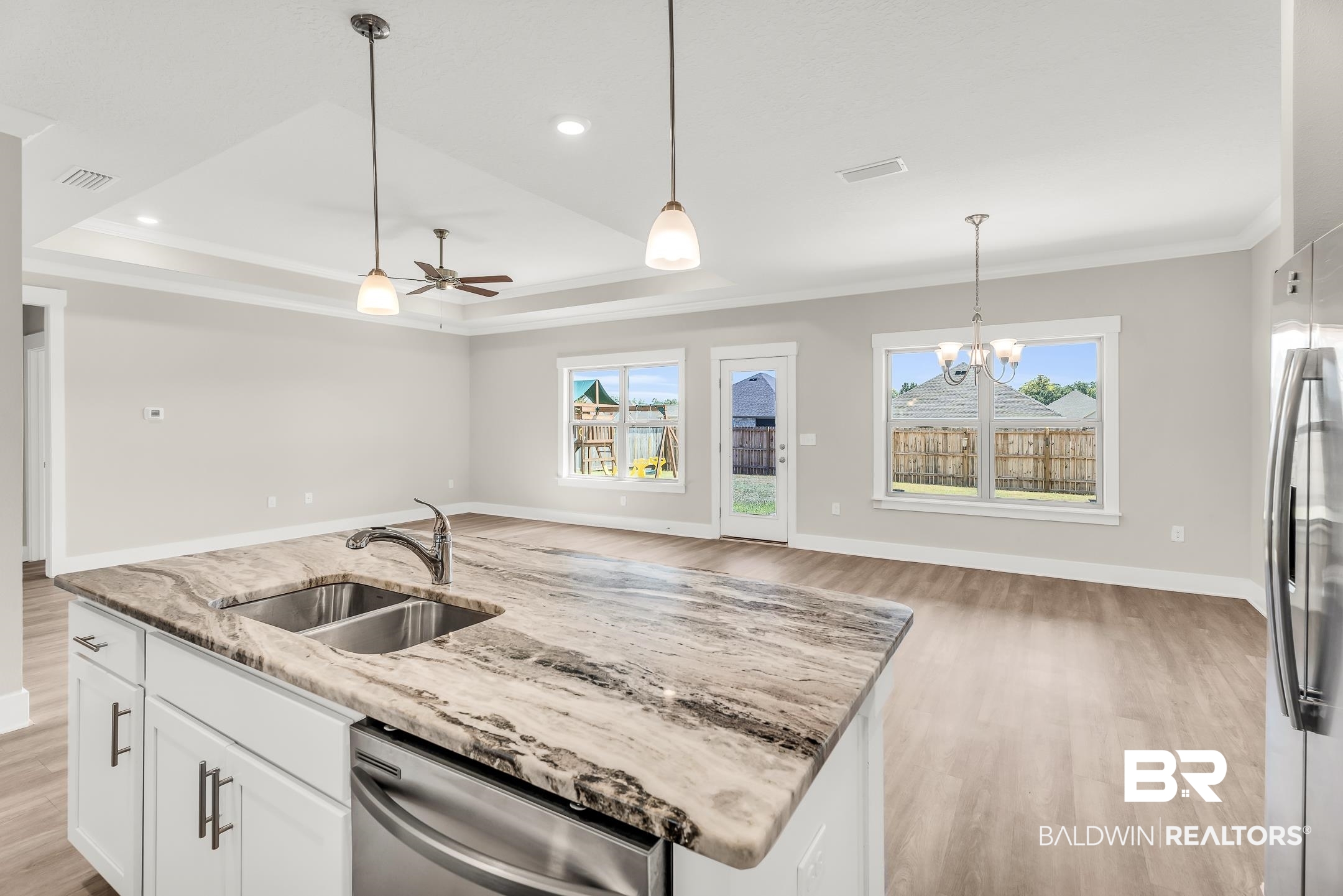 1720 Partridge Street Foley, AL 36535 - Photo 9 of 32 Kitchen featuring a raised ceiling, ceiling fan with notable chandelier, light hardwood / wood-style floors, sink, and stainless steel appliances