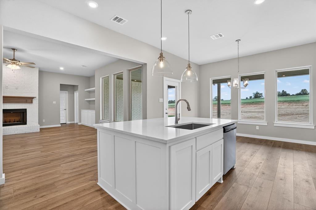 504 Clifton Court Springtown, TX 76082 - Photo 14 of 36 Modern kitchen island with a white solid surface countertop, undermount sink, and stainless steel dishwasher