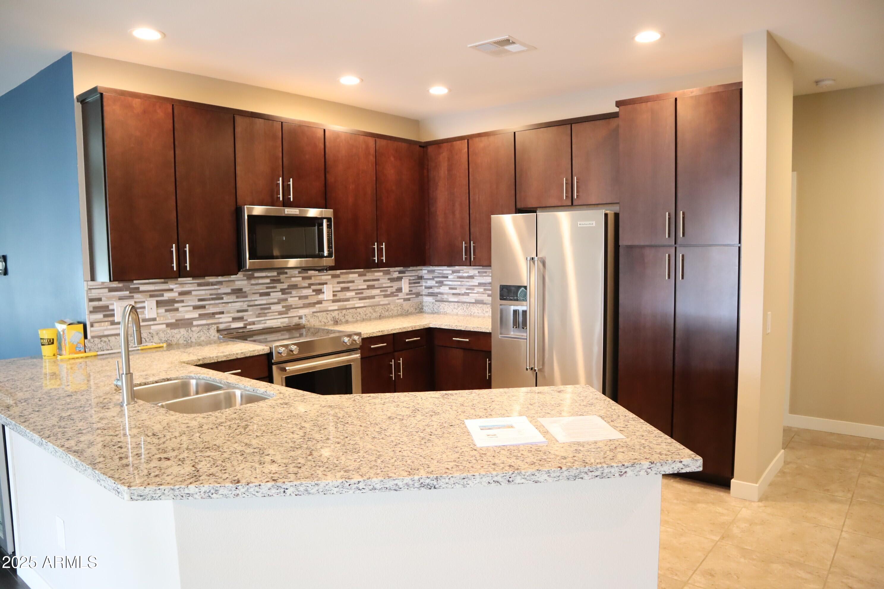 2511 West Queen Creek Road, Unit 326 Chandler, AZ 85248 - Photo 4 of 32 a kitchen with stainless steel appliances granite countertop a refrigerator and a sink