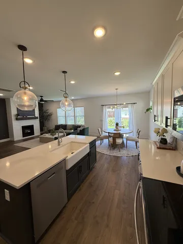 a large kitchen with kitchen island a stove a sink a dining table and chairs with wooden floor