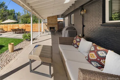 a view of a patio with couches table and chairs under an umbrella with a barbeque grill and plants