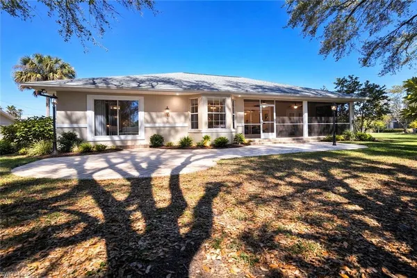 a backyard of a house with large trees and outdoor seating