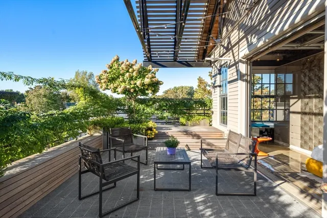 a roof deck with table and chairs and potted plants