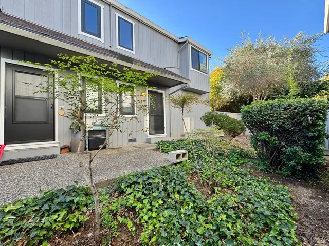 a view of a house with potted plants and a bench