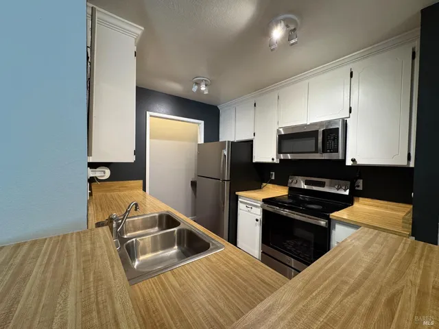 a kitchen with stainless steel appliances granite countertop a refrigerator a stove and a sink with wooden floor