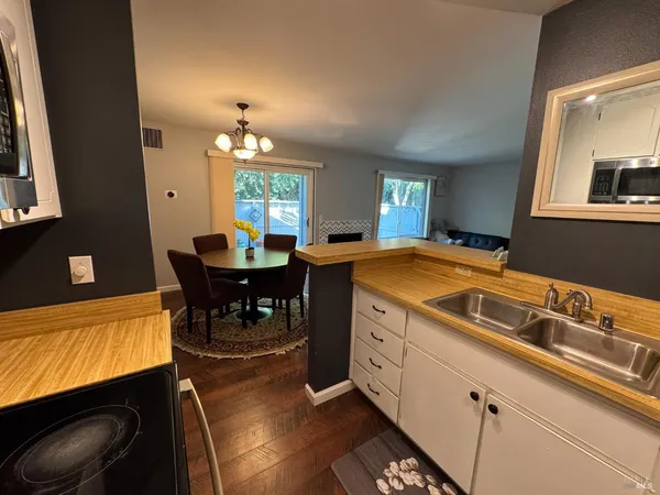 a living room with stainless steel appliances furniture a rug and a kitchen view