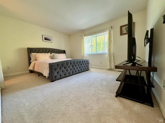 a bedroom with a bed and a dresser next to a window
