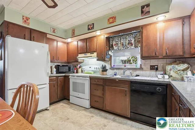 a kitchen with stainless steel appliances granite countertop a refrigerator sink and wooden cabinets