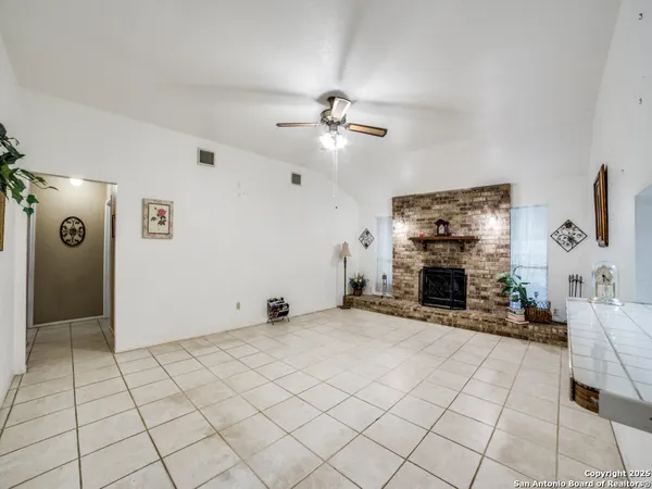 a view of an empty room with fireplace and a chandelier fan