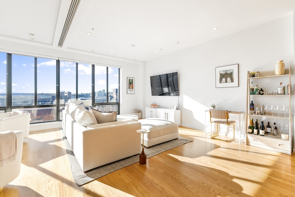 36 A Street, Unit 5C Boston, MA 02127 - Photo 5 of 25 a living room with furniture large windows and a flat screen tv