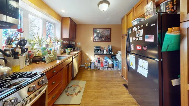 a kitchen with stainless steel appliances granite countertop wooden cabinets a sink and dishwasher with wooden floor