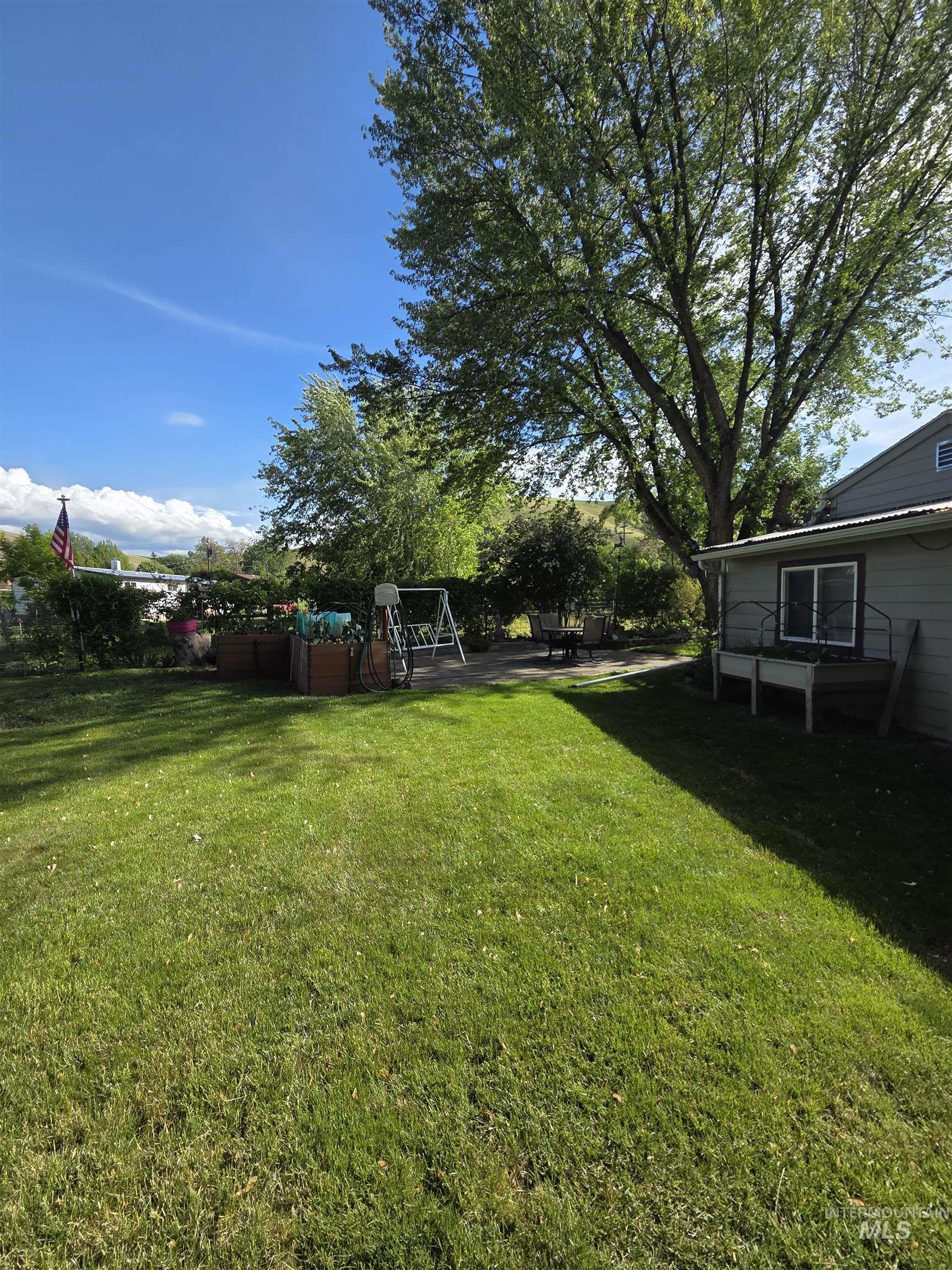 109 South 3rd Street Pomeroy, WA 99347 - Photo 30 of 36 Expansive backyard featuring a manicured lawn, mature trees, and a paved patio area