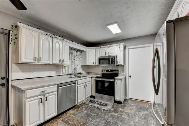 a kitchen with stainless steel appliances a refrigerator sink and white cabinets