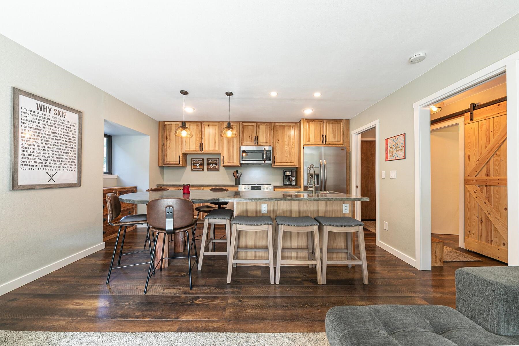 a kitchen with stainless steel appliances granite countertop a stove top oven a refrigerator a dining table and chairs with wooden floor