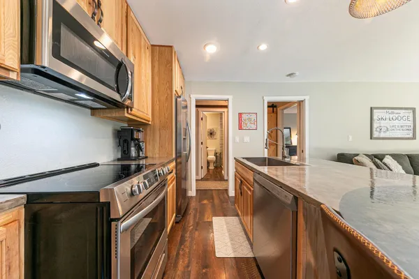 a kitchen with stainless steel appliances granite countertop a sink a stove and a wooden floors