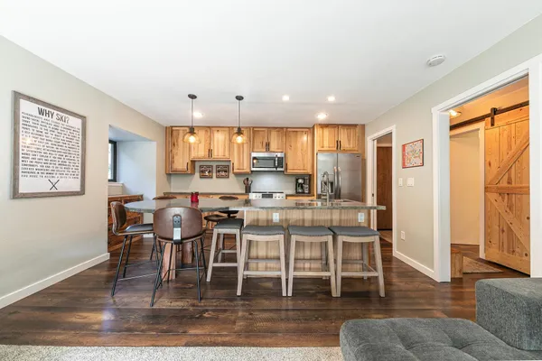 a kitchen with stainless steel appliances granite countertop a stove top oven a refrigerator a dining table and chairs with wooden floor