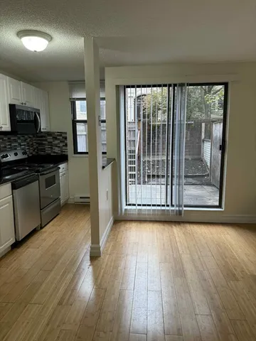 a view of a kitchen with wooden floor electronic appliances and windows