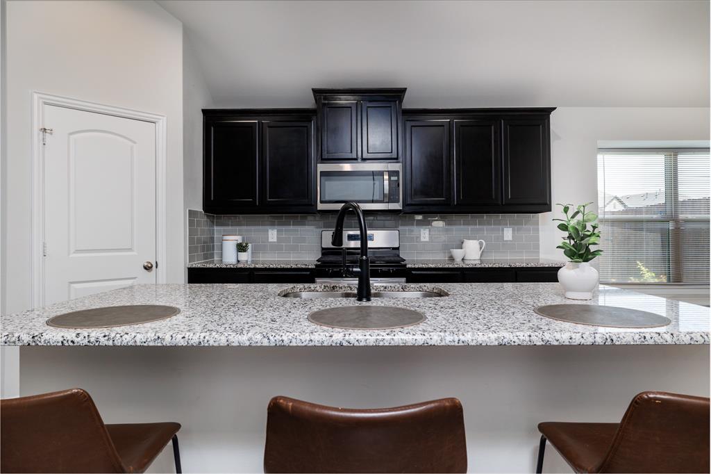 118 Sycamore Street Balch Springs, TX 75181 - Photo 13 of 34 a kitchen with granite countertop a sink a stove a window and a cabinets