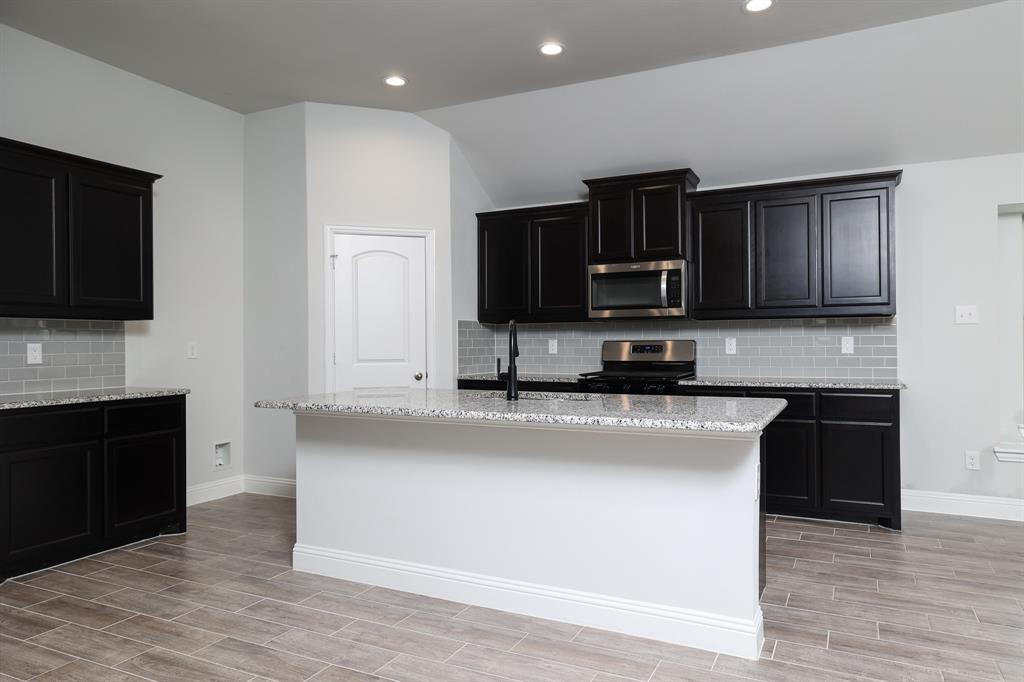 118 Sycamore Street Balch Springs, TX 75181 - Photo 17 of 34 a kitchen with kitchen island granite countertop a stove top oven a sink with granite countertops and cabinets