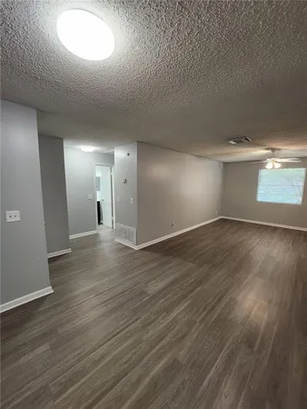 an empty room with wooden floor and windows