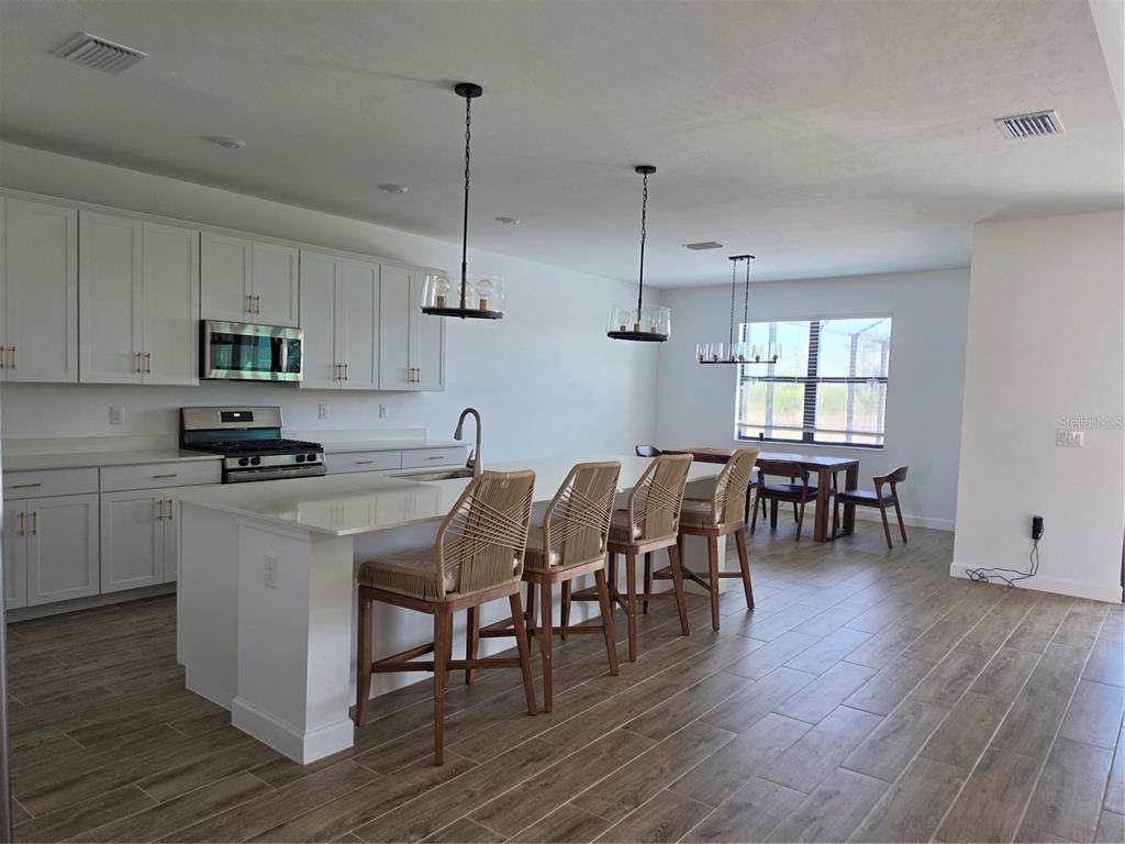 18334 Ridgeline Drive Estero, FL 33928 - Photo 4 of 30 a kitchen with stainless steel appliances granite countertop wooden floors sink table and chairs