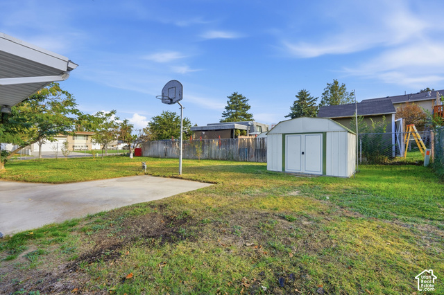 1127 Electra Lane Sandy, UT 84094 - Photo 26 of 27 Expansive backyard featuring a concrete patio, a detached storage shed, and perimeter fencing